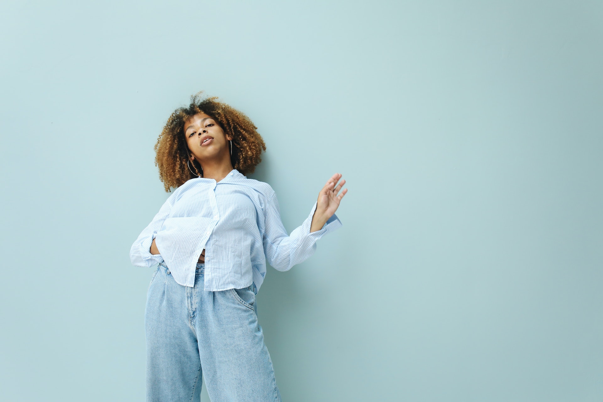Black woman with natural hair standing against a light blue wall